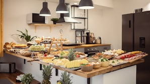 A kitchen with a buffet table filled with various food items, a microwave, and a refrigerator. - Palermo Inn Boutique Hotel  (Palermo)
