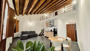 A modern interior with a wooden ceiling, a dining area with a round table and chairs, a grey sofa, and a kitchen in the background. - Palermo Inn Boutique Hotel  (Palermo)