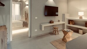 A modern hotel room with a bed, a TV mounted on the wall, a small stool, and a side table with a lamp. - Palermo Inn Boutique Hotel  (Palermo)
