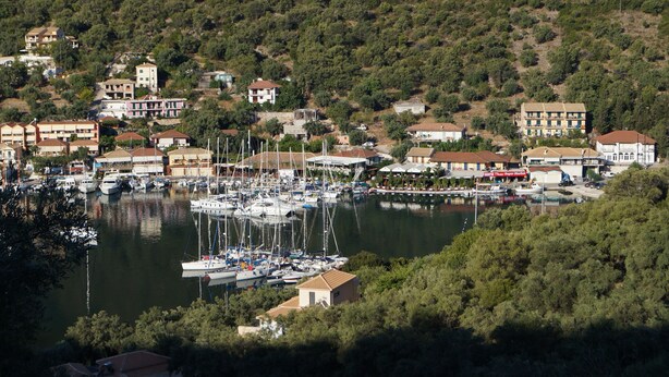 A marina with multiple boats docked, surrounded by residential buildings and greenery. - Eumaeos Spitakia (Σύβοτα Λευκάδας)