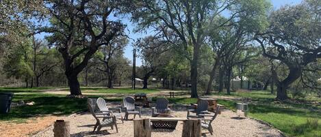 Un espace extérieur aménagé avec des tables et des chaises pour pique-niquer, entouré d’arbres.