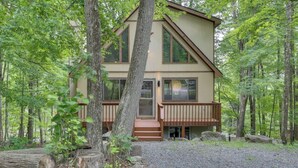 A two-story cabin with a deck, surrounded by a forest. - Lakes and Beaches with Resort Amenities at The Hideout (Hamlin)