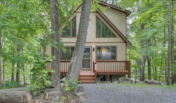 A two-story cabin with a deck, surrounded by a forest. - Lakes and Beaches with Resort Amenities at The Hideout (Hamlin)