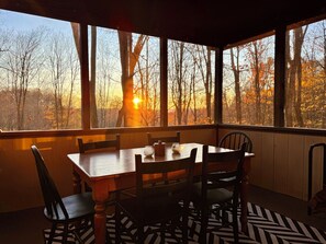 A dining area with a table and chairs, large windows with a view of trees and a sunset. - Lakes and Beaches with Resort Amenities at The Hideout (Hamlin)