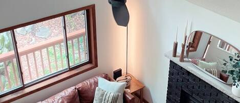 A living room with a brown leather sofa, a wooden coffee table, a fireplace, and a ceiling fan.