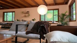 A modern living room with a wooden ceiling, a round hanging light, and a view of greenery outside. - Lakes and Beaches with Resort Amenities at The Hideout (Hamlin)