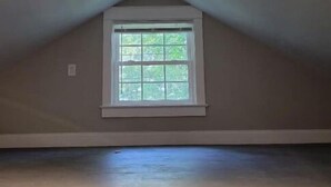 A room with a sloped ceiling and a small window.