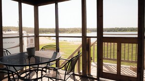 A covered outdoor seating area with a table and chairs, overlooking a lake and a boat named "COUGAR" in the background. - Willow Springs Marina (Mead)