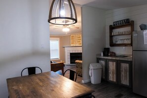 A kitchen with a wooden table, a ceiling fan, and a sign above the refrigerator that reads "Market Fresh."