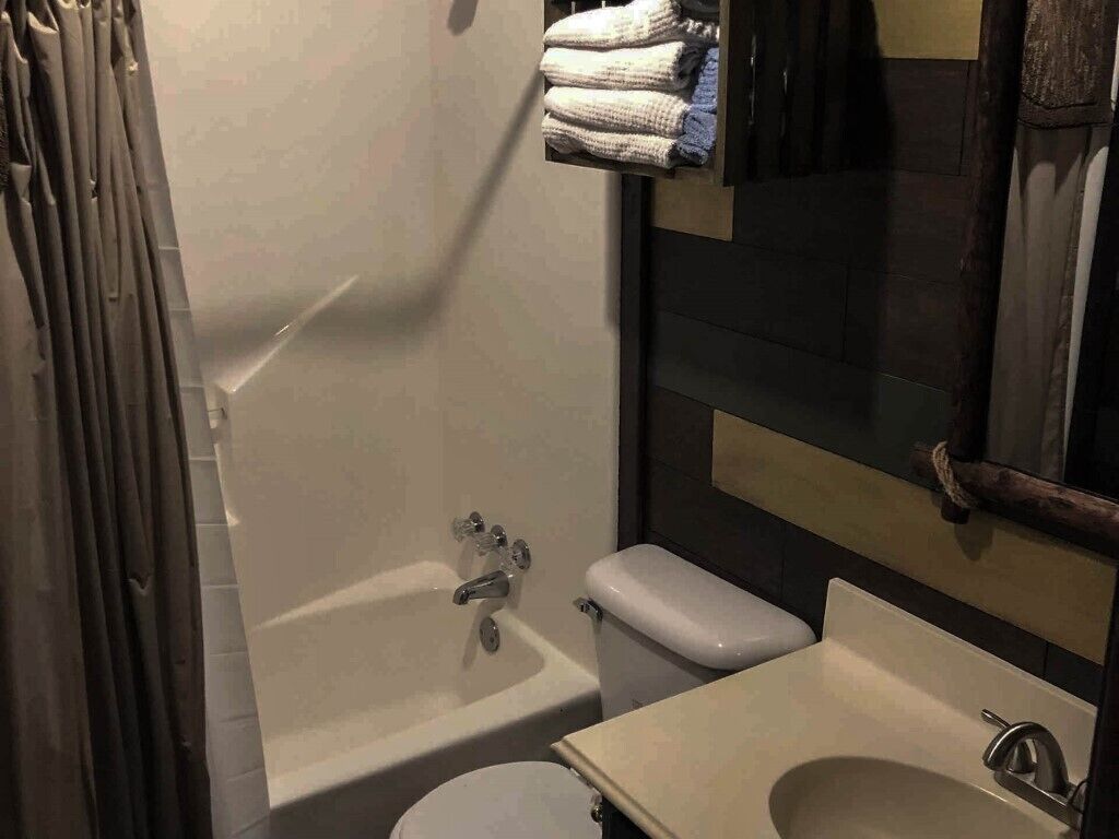 A bathroom with a bathtub, toilet, and sink. There are towels hanging on a rack above the bathtub.