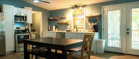 Une cuisine équipée d’une table à manger, de chaises, d’un réfrigérateur, d’un four, d’un four à micro-ondes et d’un ventilateur de plafond.