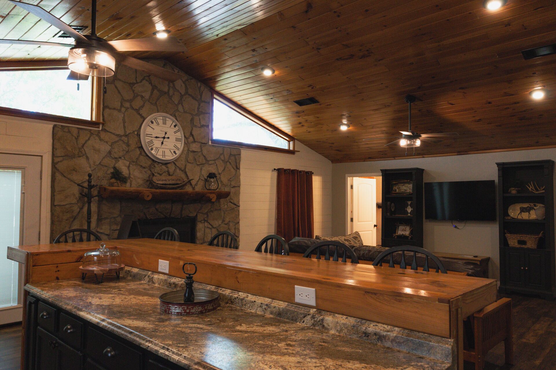 Une cuisine rustique avec un mur en pierre, un plafond en bois et un grand îlot central doté de tabourets de bar.