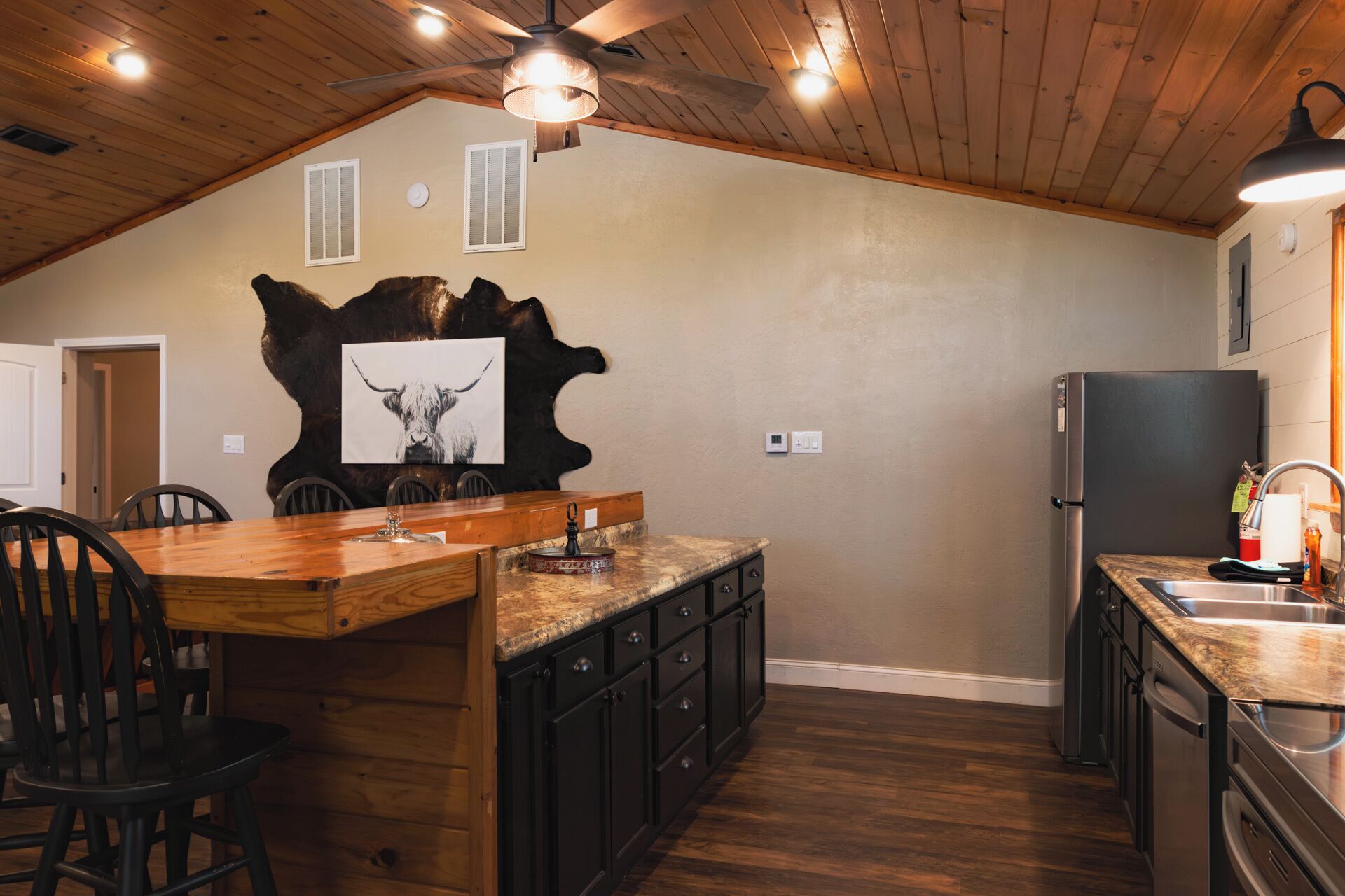 A kitchen with a wooden ceiling, a central island, and a refrigerator.
