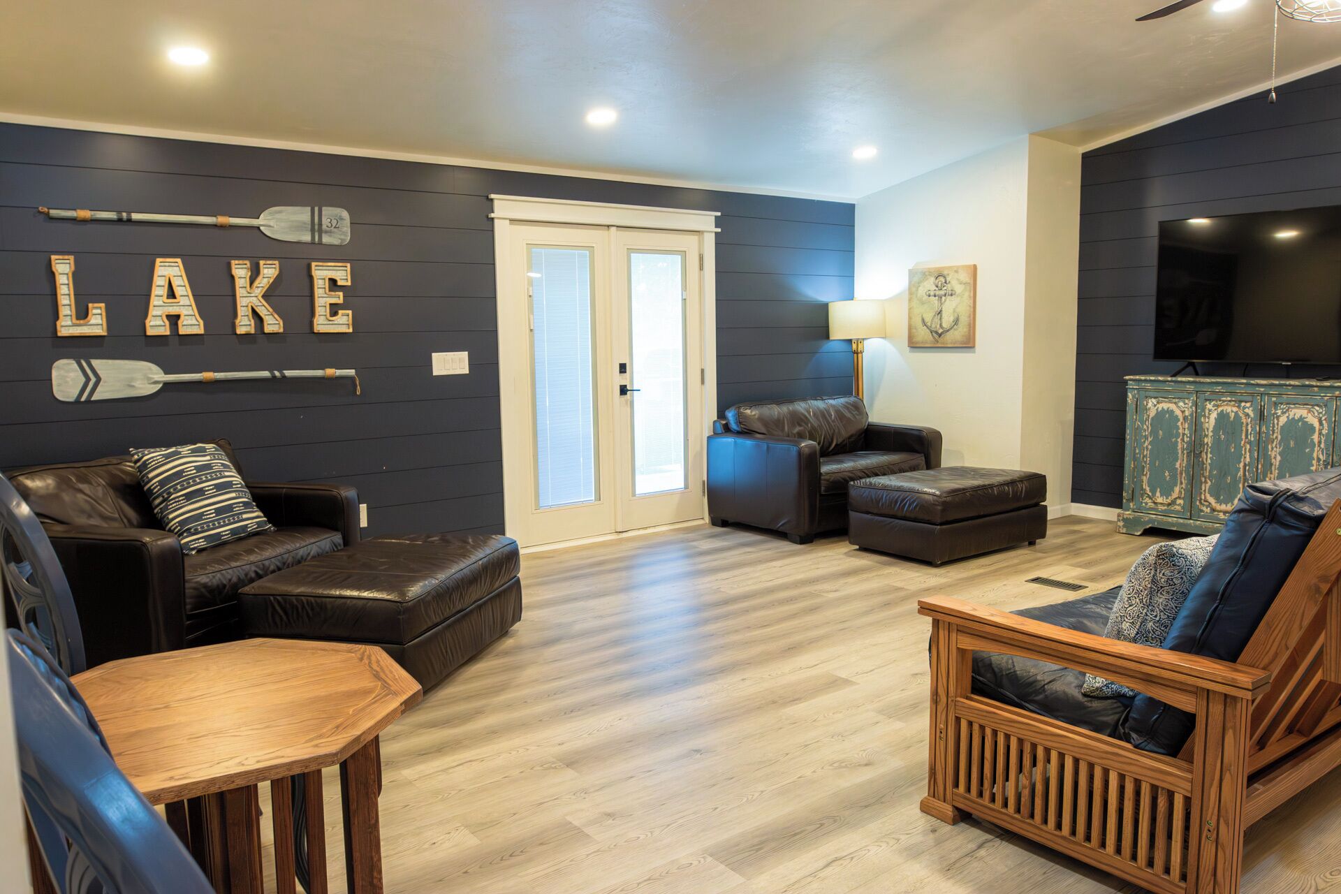 Een moderne woonkamer met een donkere muur, houten vloeren en een zithoek met leren banken en een houten salontafel.