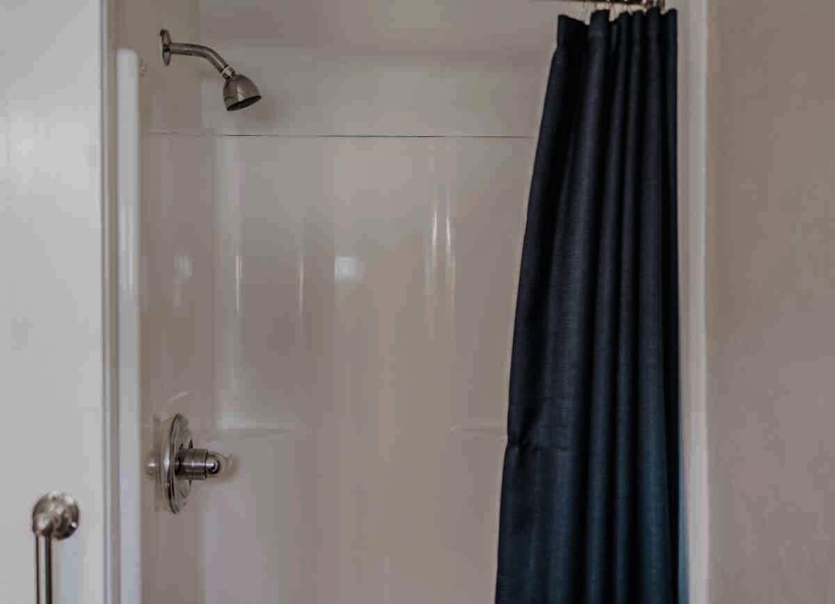 Un bagno con doccia, una porta e una tenda.