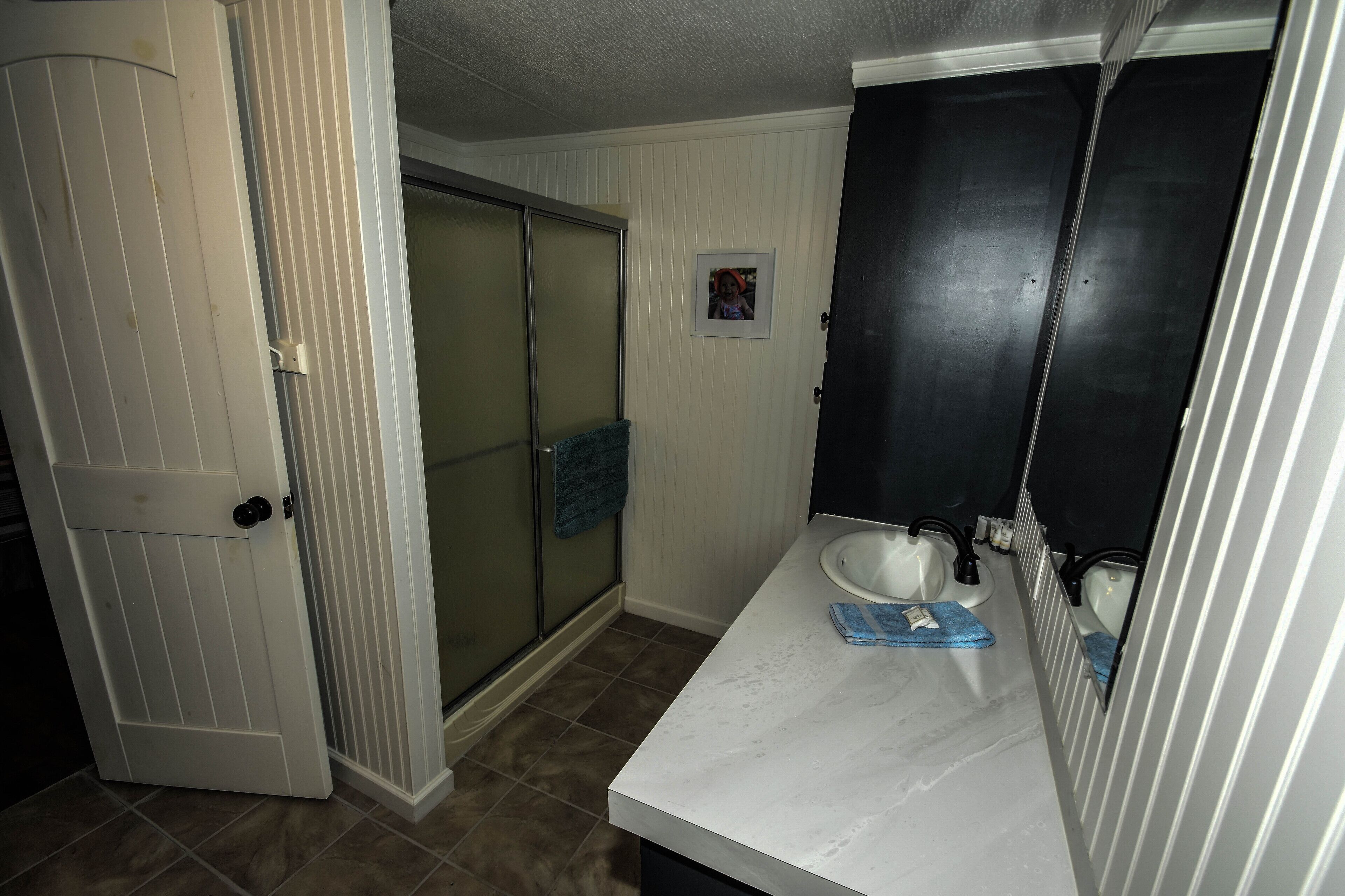 A bathroom with a white sink, a mirror, and a towel hanging on the wall.