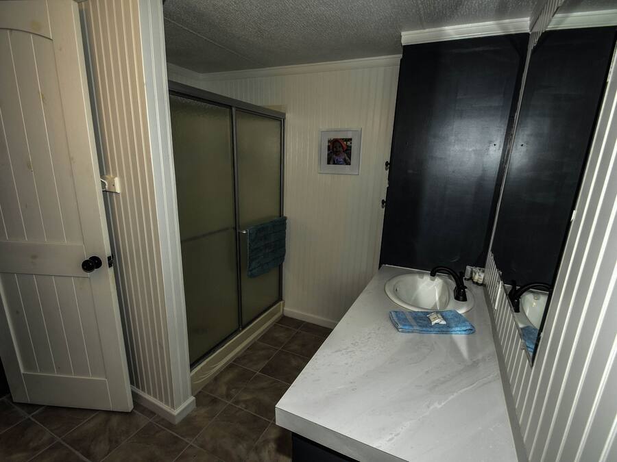 A bathroom with a white sink, a mirror, and a towel hanging on the wall.