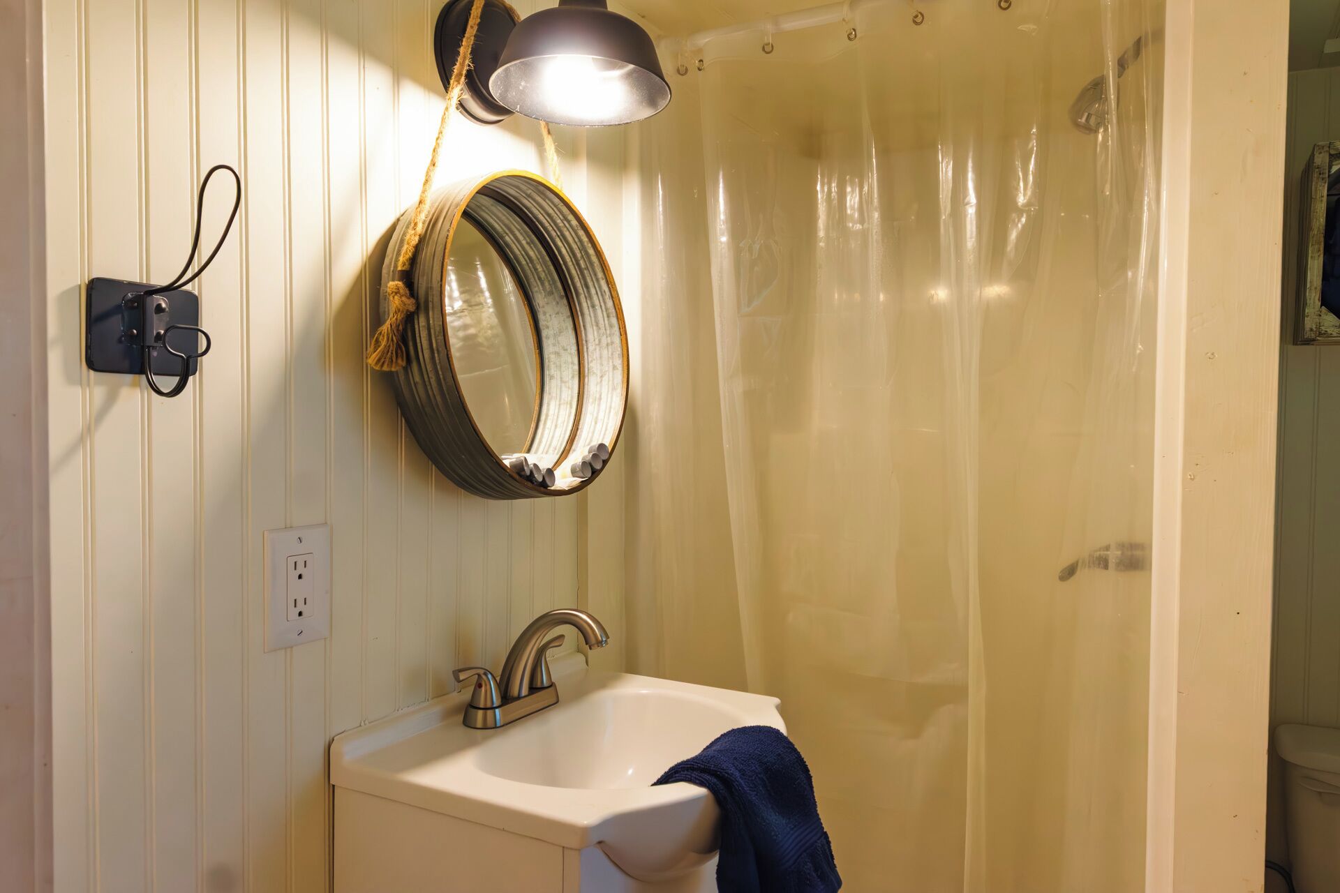 Un baño con lavamanos, espejo y cortina de ducha.