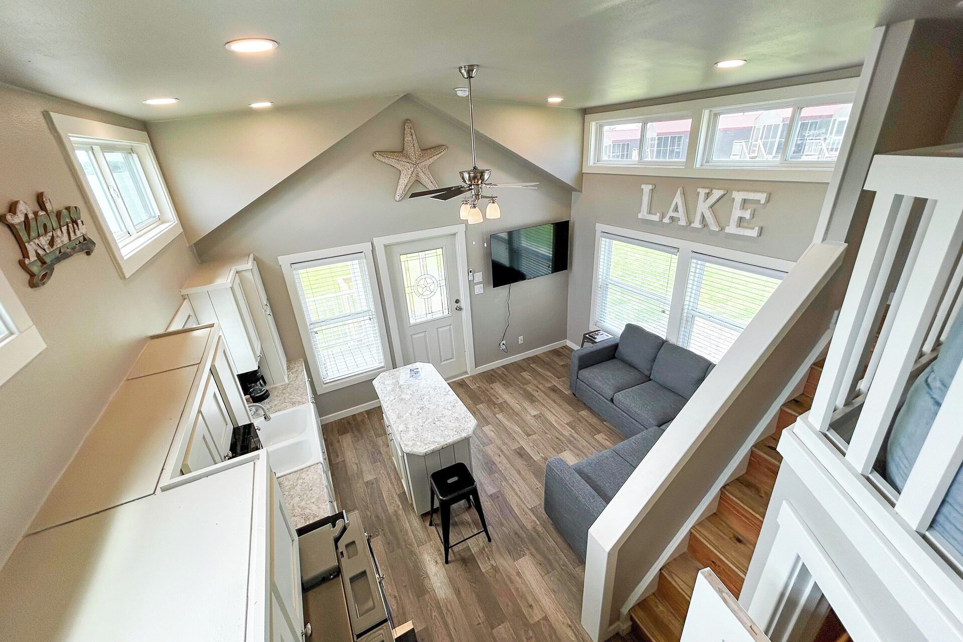 A spacious living area with a large window, a ceiling fan, and a flat-screen TV.