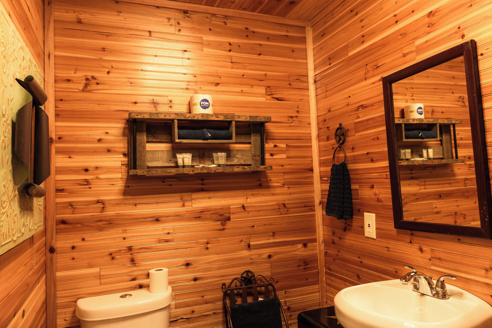 A wooden-paneled bathroom with two sinks, a toilet, and a mirror.