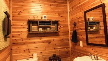 A wooden-paneled bathroom with two sinks, a toilet, and a mirror.