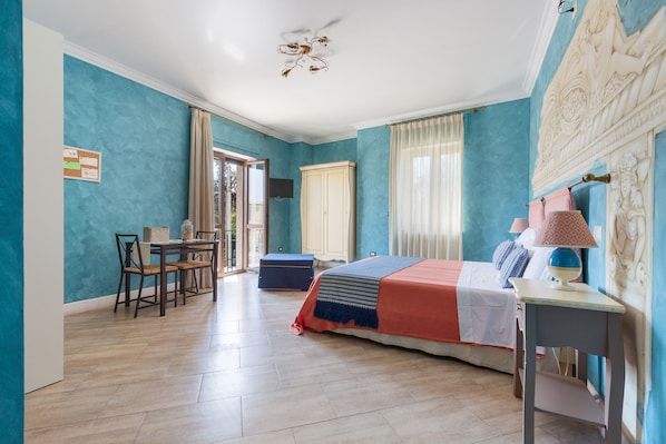 A bedroom with a bed, a desk, a chair, a wardrobe, and a dining table.