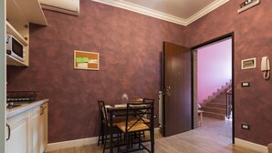 Un comedor con una mesa y sillas, un tablón de anuncios y un microondas en la encimera.