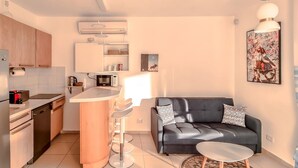 A compact kitchen with modern appliances, a central island, and a seating area with a sofa and coffee table. - Dizengoff Muguet in Tel Aviv-yafo (Tel Aviv)