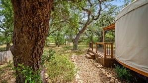 A rustic outdoor area with a large tree, a wooden deck, and a covered structure. - Ot 3515e Texas Yurt Haus: 5 Yurts! 5 Bedroom Cabin by RedAwning (New Braunfels)