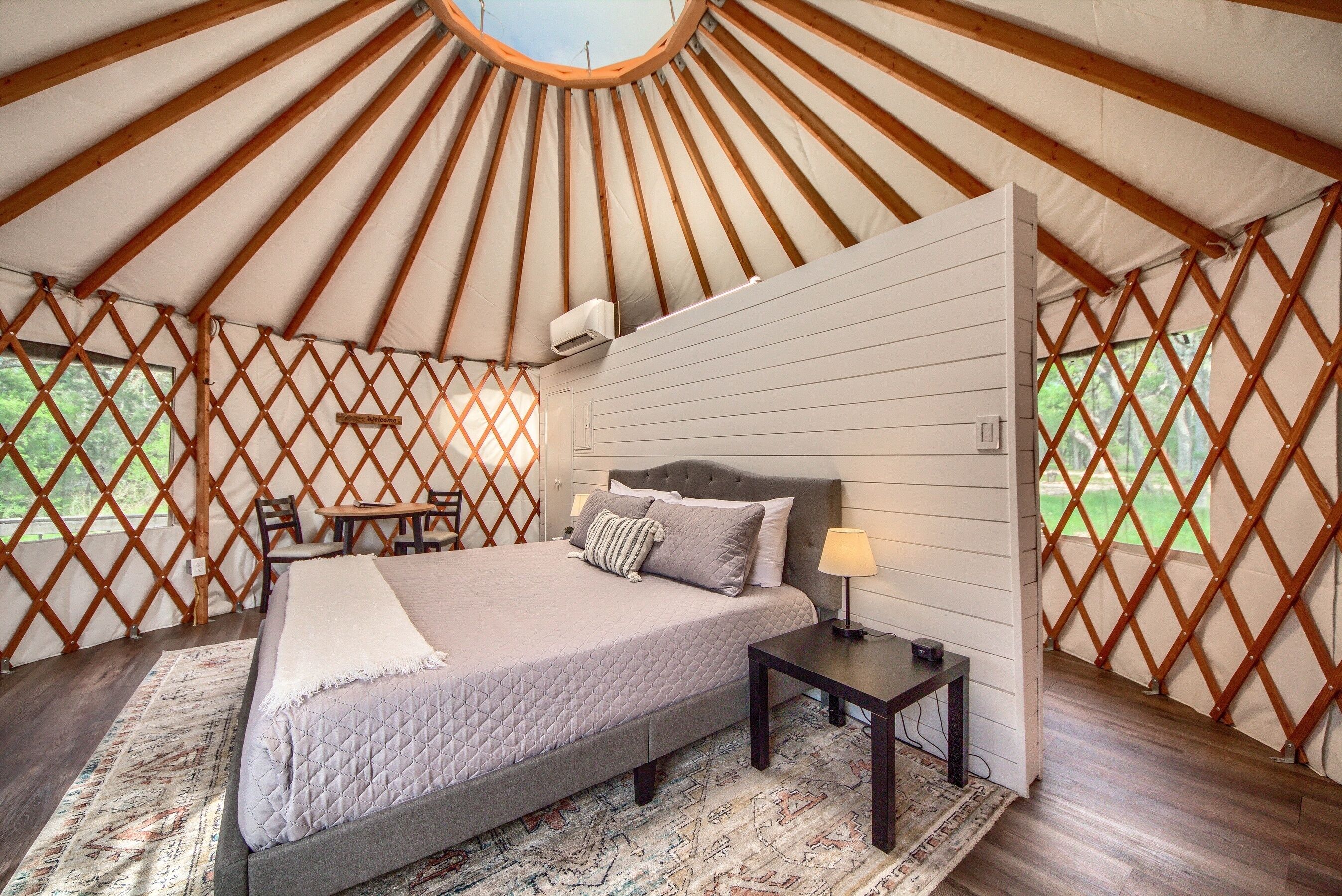 A spacious room with a large bed, a bedside table, and a window.