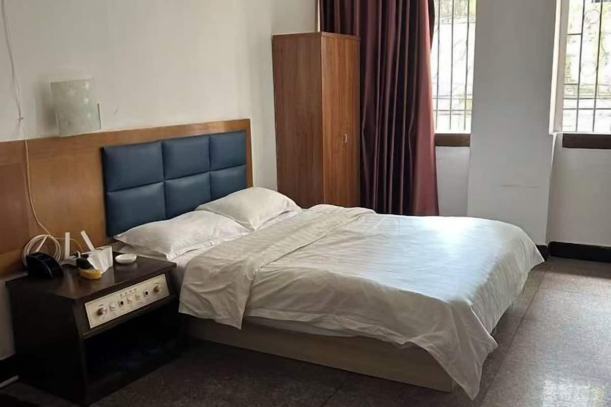 A bedroom with a bed, a wooden headboard, a nightstand, and a wardrobe.