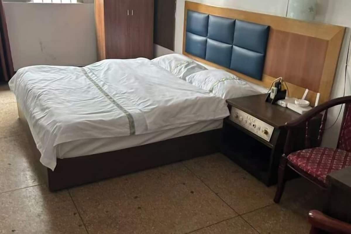 A hotel room with a bed, a nightstand, a chair, and a wardrobe.