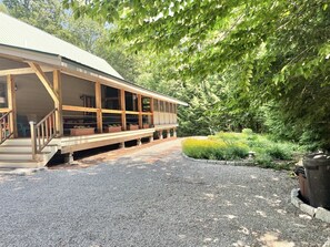 Un bâtiment en bois doté d’un porche couvert et d’une allée gravillonnée.