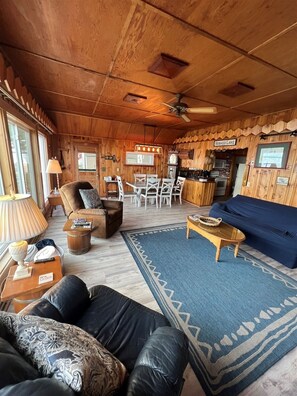 Un intérieur de chalet chaleureux comprenant un coin repas, une cuisine et un espace salon.