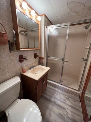 Une salle de bain équipée de toilettes, d’un lavabo, d’un miroir et d’une douche.