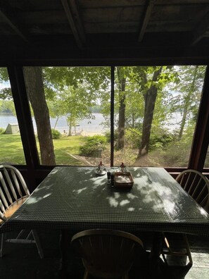 Une table recouverte d’une nappe à carreaux, avec deux salières et un petit récipient, le tout placé devant un paysage composé d’un lac et d’arbres.