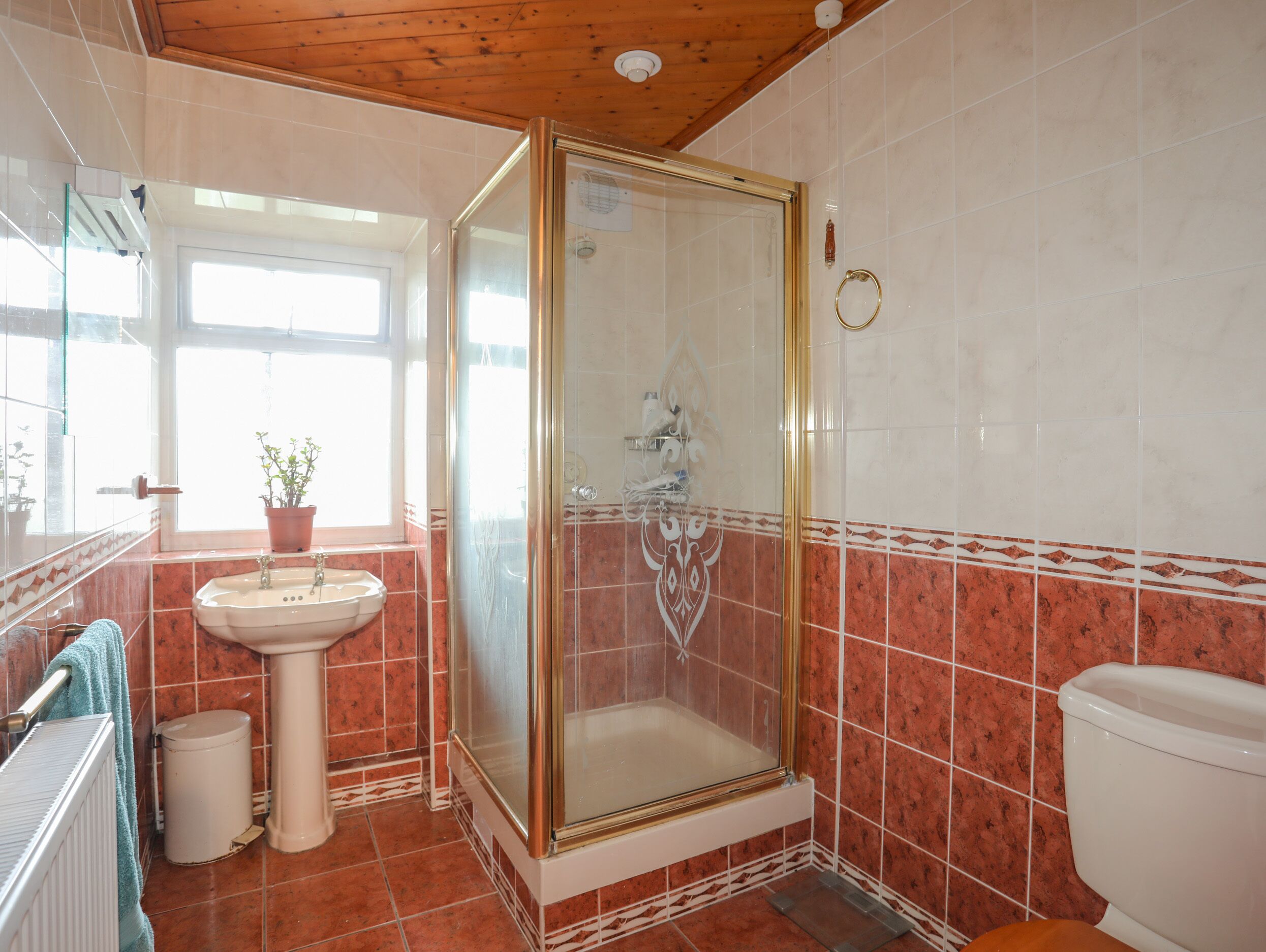 Un baño con ducha de vidrio, lavamanos e inodoro.