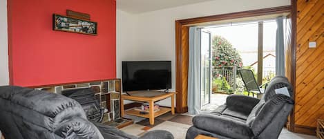A living room with a TV, two black sofas, a coffee table, and a red accent wall.