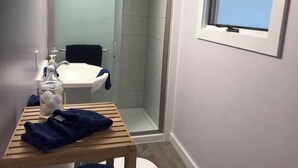 Un baño con lavamanos blanco, cabina de ducha de vidrio y ventana.