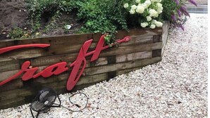 Una jardinera de madera con un letrero rojo con escritura cursiva que dice 'craft'.