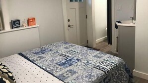 Un dormitorio con cama, una puerta, un ventanal y una estantería con dos letreros.