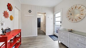 A hallway with a red bench, a white console table, and a decorative mirror on the wall. - Charming Sweet Daisy overlooking stunning new pool in awesome Southside Village! (Sarasota)