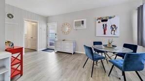 A dining area with a round table, blue chairs, and a white cabinet. - Charming Sweet Daisy overlooking stunning new pool in awesome Southside Village! (Sarasota)