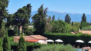 A view of a property with a pool, umbrellas, and a mountainous backdrop.