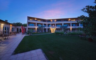 A multi-story hotel with outdoor seating and a well-maintained lawn.