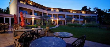 Un hotel con asientos al aire libre y un patio bien iluminado.