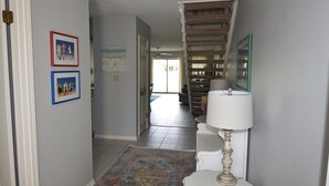 A hallway with a patterned rug, a white lamp, and framed pictures on the wall. - 2 D, Three Bedroom Townhome (Miramar Beach)