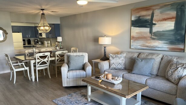 A modern living room with a sofa, armchair, coffee table, and dining area. - 2 D, Three Bedroom Townhome (Miramar Beach)