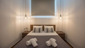 Een netjes opgemaakt bed met twee kussens, een nachtkastje en een wandlamp.