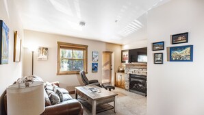 A living room with a fireplace, a sofa, a coffee table, and a TV. - Jupiter Inn (Park City)